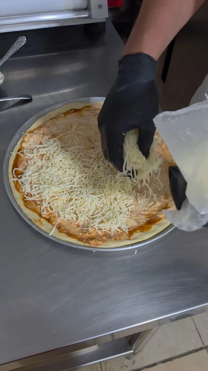 Preparación real: queso sobre la pizza de la casa